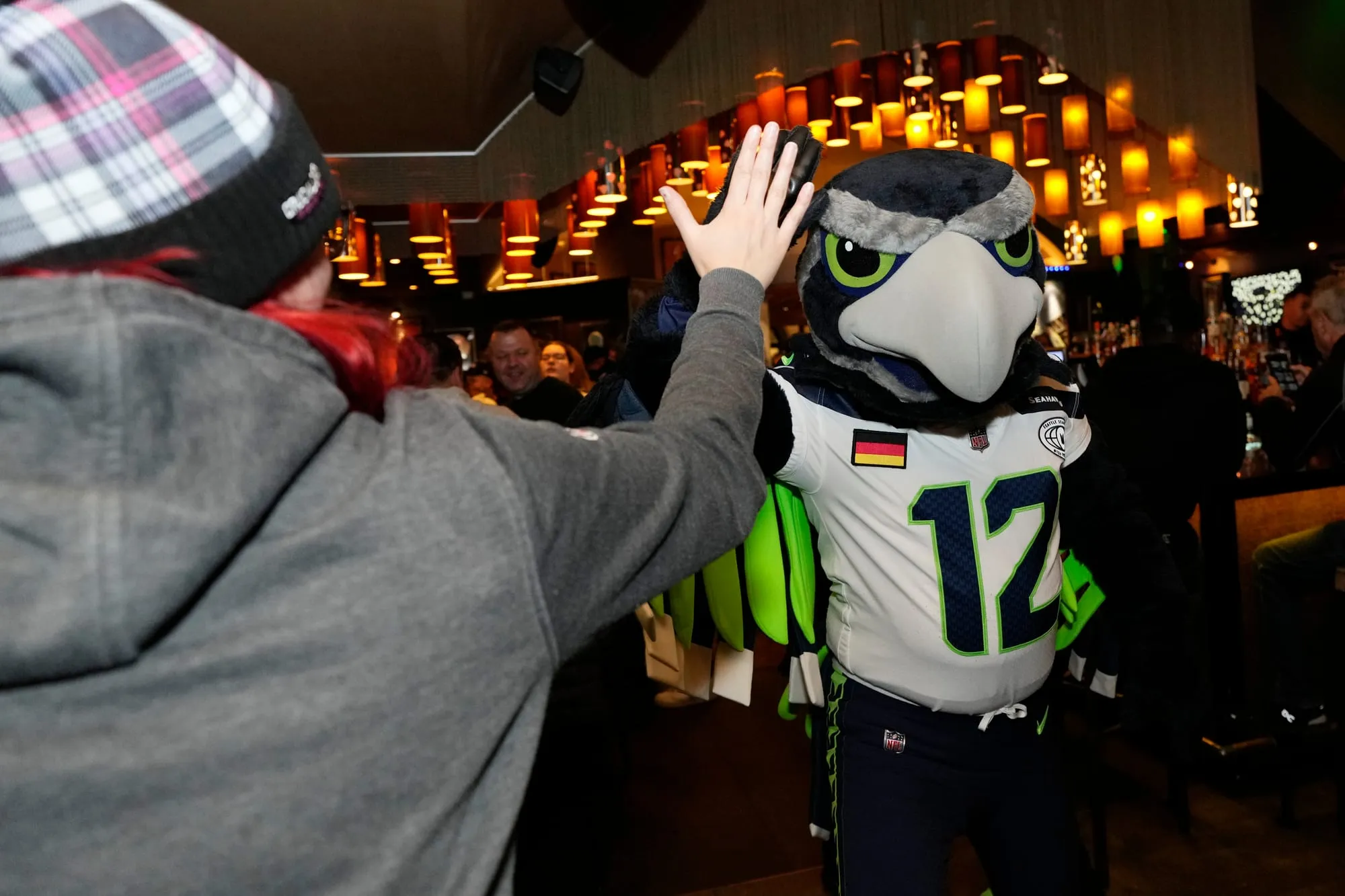 Ein Maskottchen gibt einem Fan in einer Bar ein High Five.